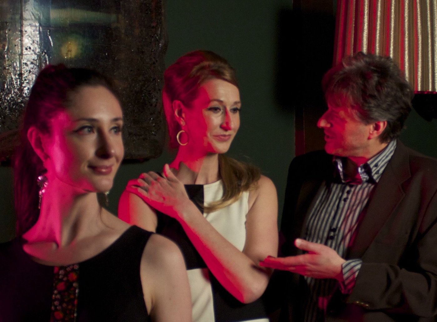 Three members of Rue '66 in conversation under red club light