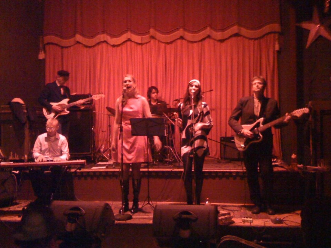 Rue '66 performing in front of a red stage curtain