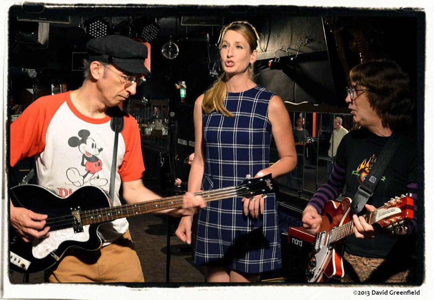 Bassist, singer and guitarist gathered at the front of the stage